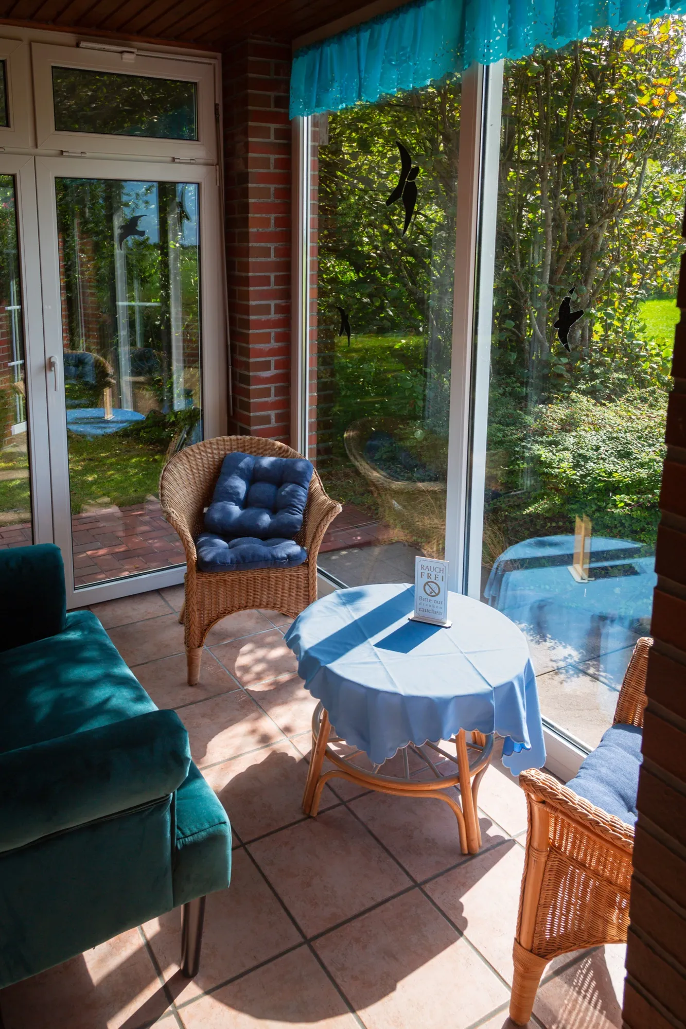 Wintergarten mit Rattansesseln, rauchfrei, Blick in den Garten