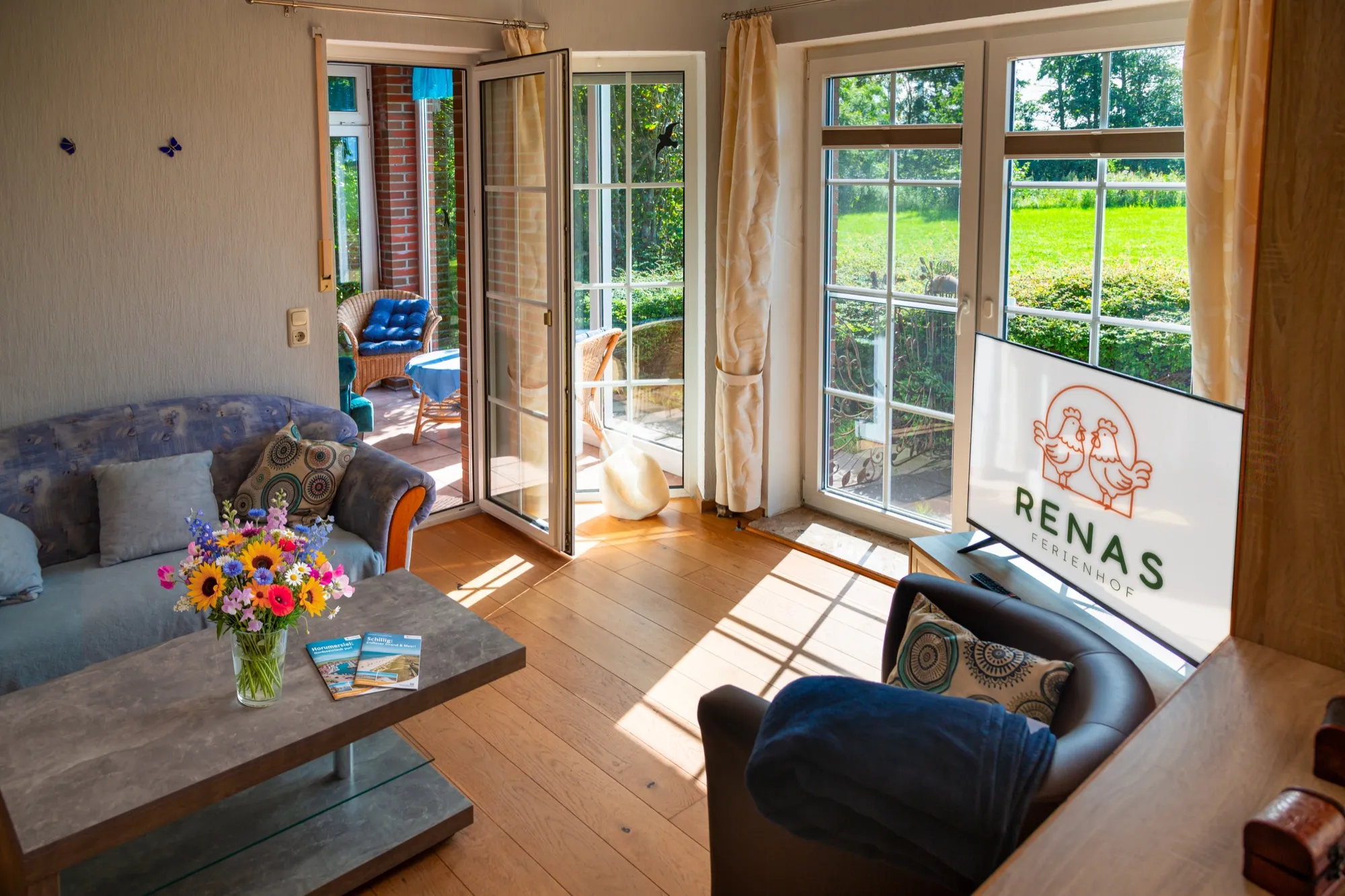 Wohnzimmerbereich mit Sofa, Couchtisch und Fernseher, Blick zum Wintergarten